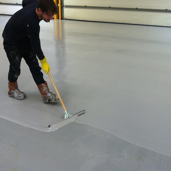 Man spreading and flattening out the two coats of grip seal, anti-slip resin