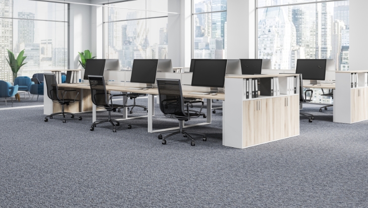 Dark grey office carpet flooring with white wood desks and view of city