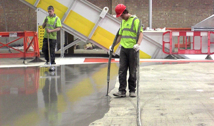 Two workmen fitting a pumped screed floor
