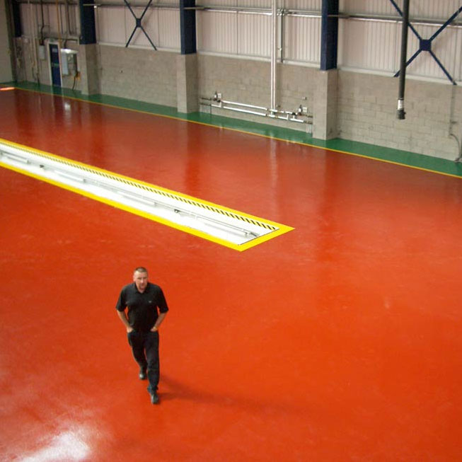 man walking across a red floor with line demarcation in a warehouse