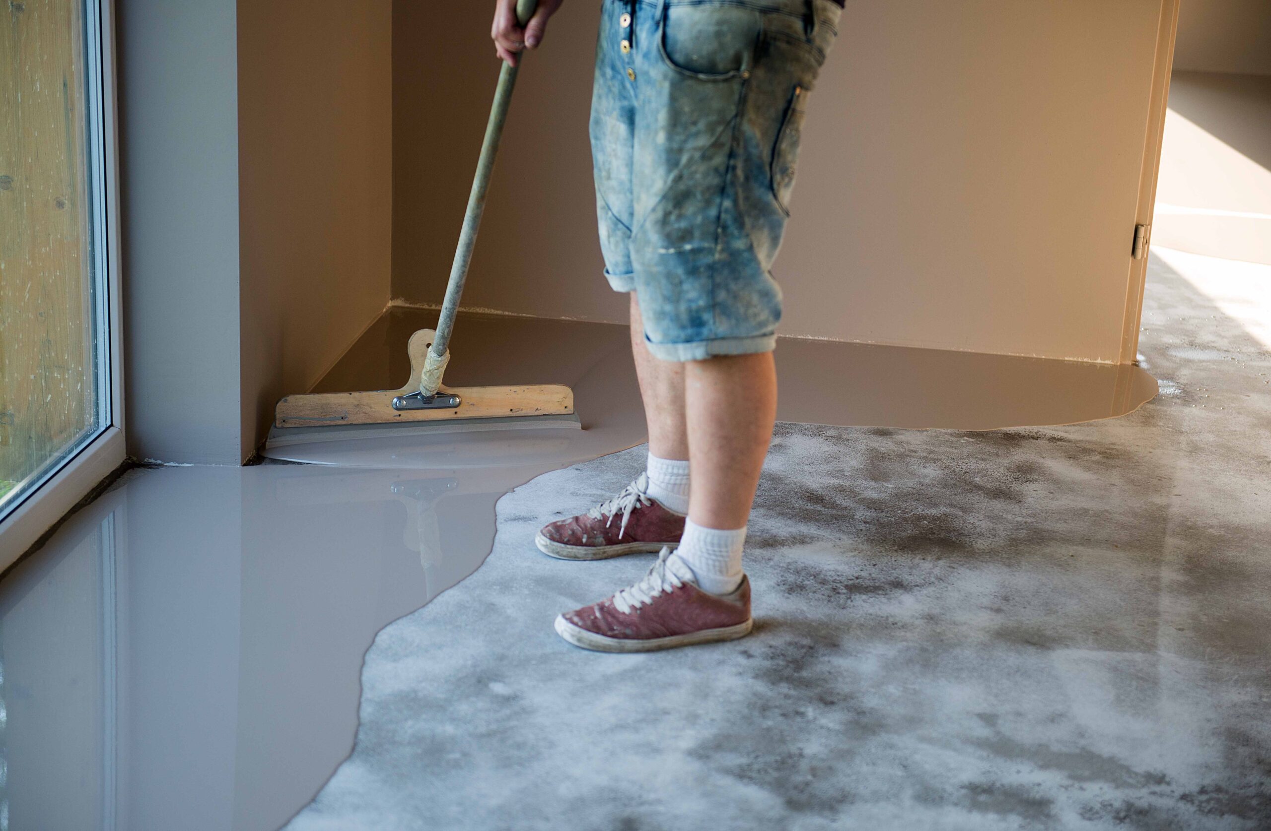 concrete flooring being spread over the top of an old epoxy floor